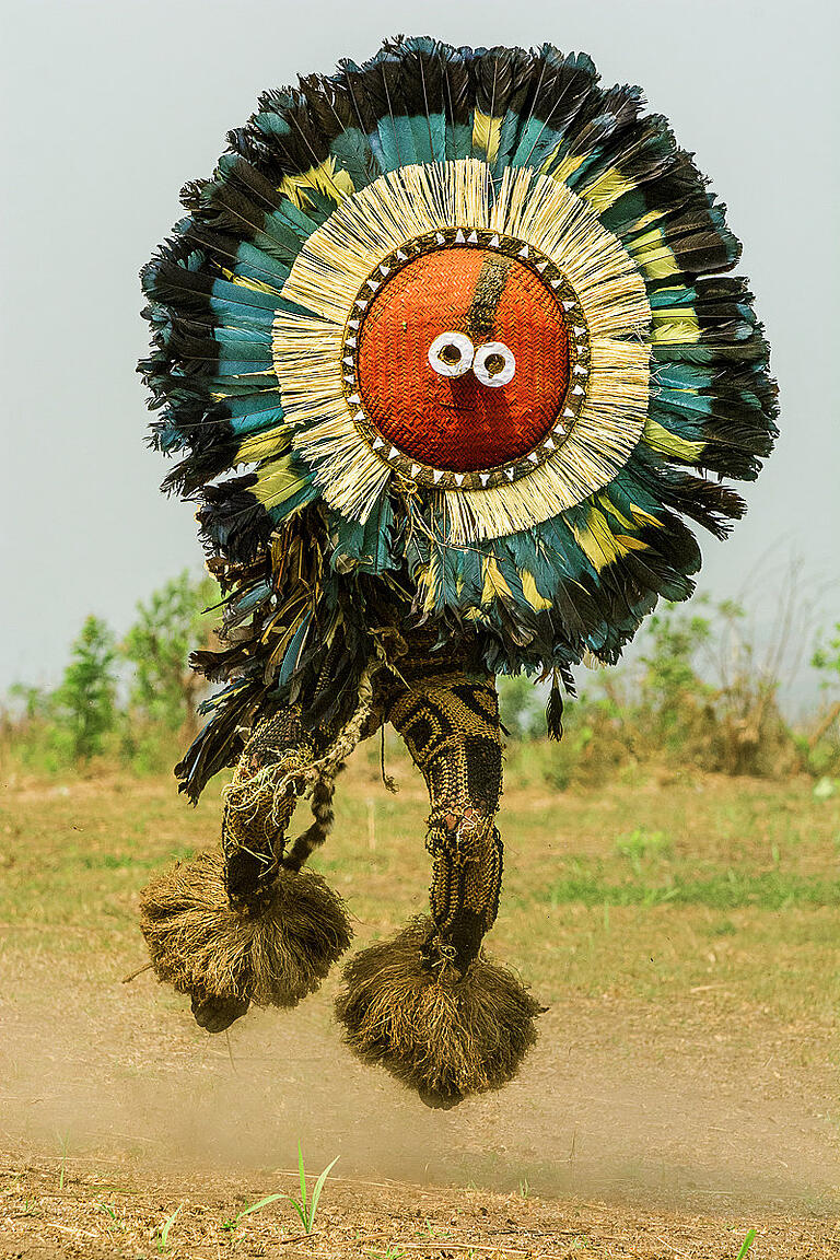 Ein Tänzer mit Kulukulu-Maske bei einem Initiationsritus im Kongo: Das runde rote Geflecht ist umringt von hunderten von Kulukulu-Federn. Ein Tänzer mit Kulukulu-Maske bei einem Initiationsritus im Kongo: Das runde rote Geflecht ist umringt von hunderten von Kulukulu-Federn. 