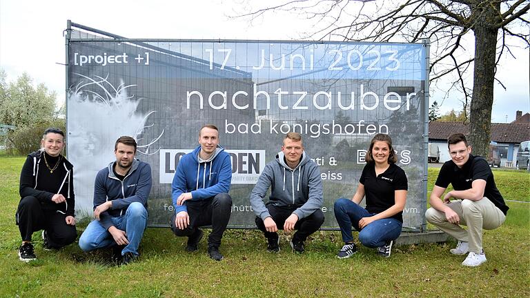 Die Vorbereitungen auf den 10. 'Nachtzauber' von [project+] sind angelaufen: Die Vereinsmitglieder (von links) Kim Filbry (Beisitzerin), Jochen Katzenberger (stellvertretender Vorsitzender), Manuel Schulz (Vorsitzender), Philipp Angermüller, Luisa Zeitz und Felix Bregulla vor einem großen Banner, mit dem in der Schweinfurter Straße am westlichen Stadtausgang von Bad Königshofen auf die große zweitägige Party im Juni hingewiesen wird.