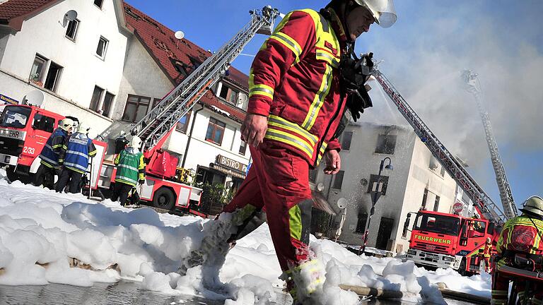 Ein Feuerwehrmann läuft durch eine Decke aus Löschschaum. Über Jahren enthielt er giftige Chemikalien, die sich in Böden und teilweise im Grundwasser ablagerten.