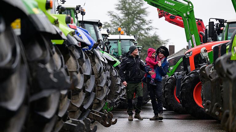 Bauern protestieren mit Traktoren.jpeg - Ein Landwirt geht mit seiner Familie an parkenden Treckern entlang. Bauern protestieren mit Traktoren.jpeg - Ein Landwirt geht mit seiner Familie an parkenden Treckern entlang.