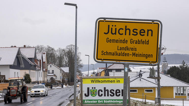 Ein Traktor fährt am Ortseingangsschild von Jüchsen vorbei. Etwa 90 Menschen haben sich am Sonntag in dem Corona-Hotspot zu einem Faschingsumzug versammelt. Ein Traktor fährt am Ortseingangsschild von Jüchsen vorbei. Etwa 90 Menschen haben sich am Sonntag in dem Corona-Hotspot zu einem Faschingsumzug versammelt.