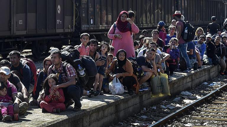 Macedonian police officers control departure of migrants heading       -  Menschen, die in Europa Hilfe suchen: Flüchtlinge warten im mazedonischen Gevgelija auf einen Zug, mit dem sie nach Serbien weiterkommen wollen.