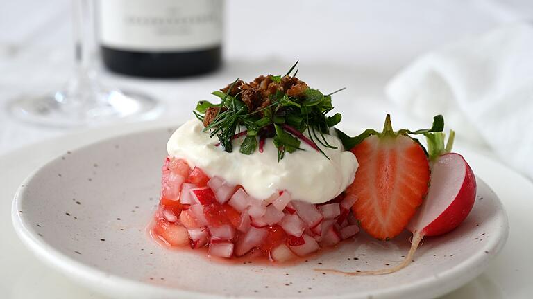 Radieschen-Erdbeer-Salat mit Ziegen-Feta-Creme       -  Der Erdbeer-Radieschen-Salat wird mit einem Servierring in Form gebracht. Darauf gibt es als Topping Ziegen-Feta-Creme, Kräutersalat und geröstete Krümel vom Schwarzbrot. Serviert wird er mit einem alkoholfreien Rosé.