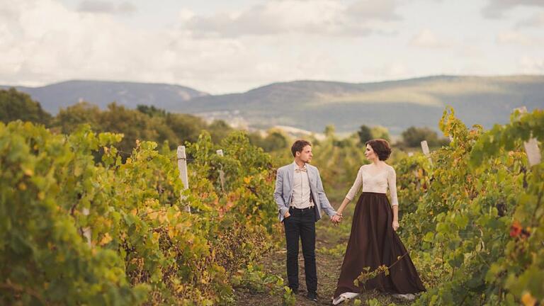 Romantic and stylish caucasian couple standing in the beautiful vineyard       -  Auf einem Weingut entstehen die schönsten Aufnahmen für die Ewigkeit.