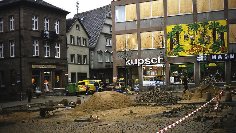 Die Linden vor der Kupsch- und Mainkauffassade stehen, die Pflasterarbeiten waren Ende Oktober 1978 noch nicht ganz abgeschlossen. Die Bäume sollten die Front des Kaufhauses verschönern. Auf dem Foto sind die Fenster noch mit Holz versehen, nachdem die Scheiben infolge der Gasexplosion im Juni zerborsten waren.