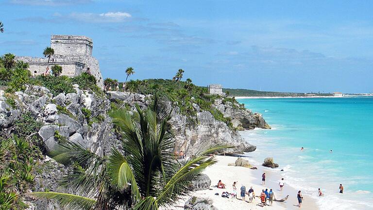 Eine Maya-Ruine und Palmen auf über dem Strand und türkisem Meer.       -  Die Deutschen zieht es wieder in den Urlaub.