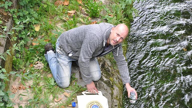 Bäcker Michael Stephan zieht eine Wasserprobe aus dem Bach in Heidingsfeld. Foto: Wilma Wolf