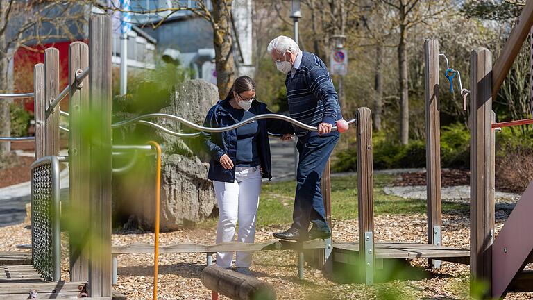 Auf dem Therapiepfad der geriatrischen Reha-Klinik in Würzburg trainiert Ergotherapeutin Mareike Marten mit Michael von Preuschen-Lewinski den Gleichgewichtssinn. Nach einer schweren Erkrankung möchte der 85 - Jährige bald wieder alleine spazieren gehen können.