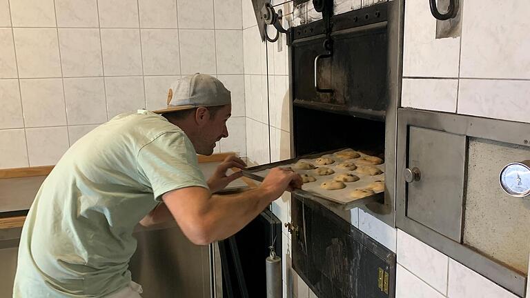 Steffen Schneider schiebt ein Bleck mit Backwaren in den Ofen des Dorfbackhauses. Das Haus ist dank ehrenamtlichem Engagement der Dorfbewohner neu gestaltet. Foto: Thomas Malz       -  Steffen Schneider schiebt ein Bleck mit Backwaren in den Ofen des Dorfbackhauses. Das Haus ist dank ehrenamtlichem Engagement der Dorfbewohner neu gestaltet. Foto: Thomas Malz