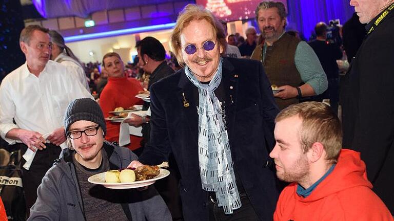 Musiker Frank Zander (M) verteilt bei seinem 25. Weihnachtsfest für Obdachlose und Bedürftige Weihnachtsgans an die Gäste. Foto: Gregor Fischer/dpa       -  Hier tischt der Star selbst auf: Frank Zander bedient bei einem seiner Weihnachtsessen die Bedürftigen.