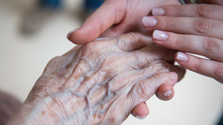 Pflege im Alter - Alt und Jung: Eine Pflegerin hält die Hand einer Bewohnerin im Seniorenzentrum. (Symbolbild) Pflege im Alter - Alt und Jung: Eine Pflegerin hält die Hand einer Bewohnerin im Seniorenzentrum. (Symbolbild)
