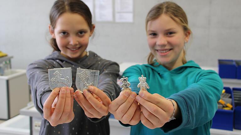 Wappen und kleine Bären aus Zinn: Sinja und Franziska zeigen das Ergebnis ihrer Arbeit. In der 'Nacht der Metalle' dürfen sich die Besucher wie an vielen anderen Stationen auch beim Zinngießen ausprobieren.