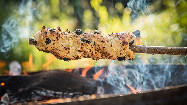 Stockbrot mit Oliven-Feta-Teig       -  Ein Oliven-Feta-Knoblauch-Hefeteig ist um einen Haselnuss-Stock gewickelt und wird über dem Lagerfeuer gebacken.