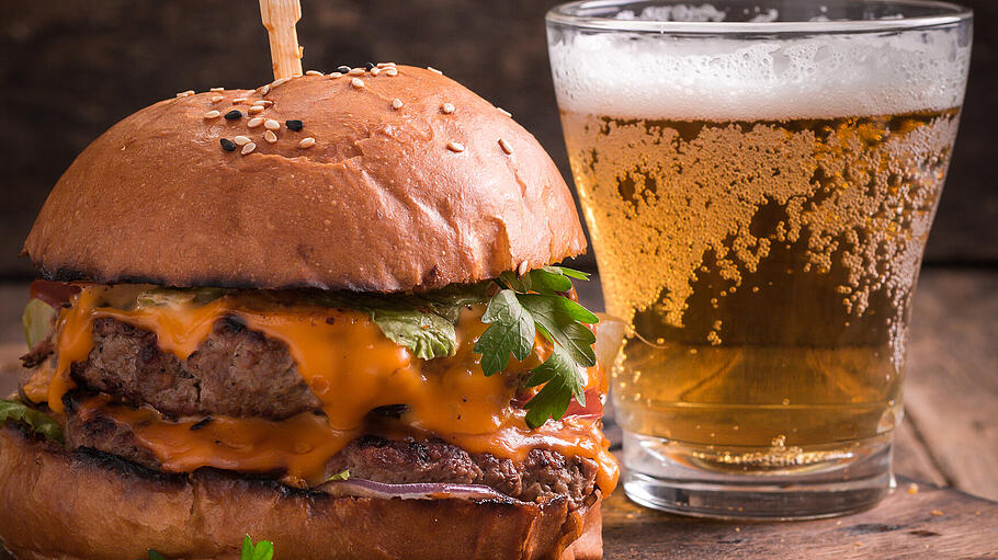 Fresh hamburger with a beer on a wooden table.       -  Fresh and tasty hamburger with a beer on a wooden table.