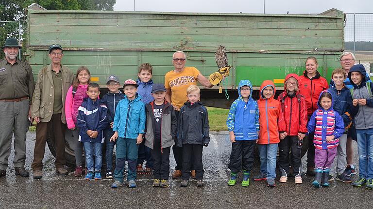 Das Foto entstand vor der Abfahrt in die Flur. Es zeigt die Kinder gemeinsam mit Jagdhelferin Caroline Dürr (links), den Waidmännern Karl Dürr und Edgar Schaub (Zweiter und Dritter von links), Falkner Ferri Gagstetter und seinem Fleckenuhu (Bildmitte) sowie Wagenlenkerin Marina Grimm (Sechste von rechts) und dem Vizevorsitzenden des SPD-Ortsvereins Kleinrinderfeld, Arnold Henneberger (Dritter von rechts).