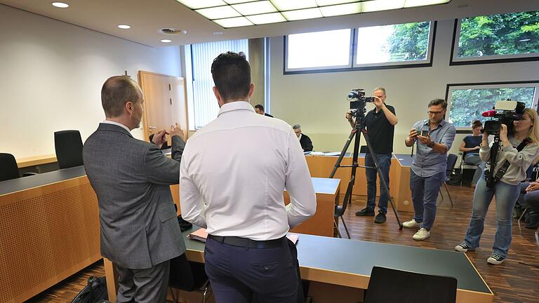 Prozess gegen Polizisten wegen Schussabgabe       -  Der Angeklagte (Mitte) steht mit seinem Anwalt im Verhandlungssaal in Augsburg.