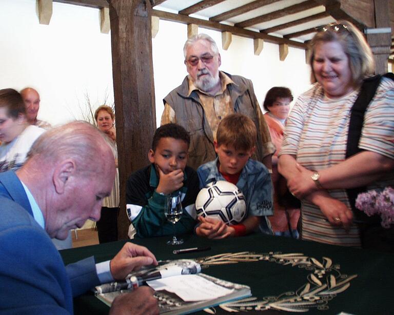 Geduldig erfüllte Horst Eckel während seines Besuchs in Gerolzhofen im Mai 2004 Autogrammwünsche. Er signierte alles vom einfachen Blatt Papier über Fußbälle bis hin zu Büchern und Bildbänden zum Thema Fußball.