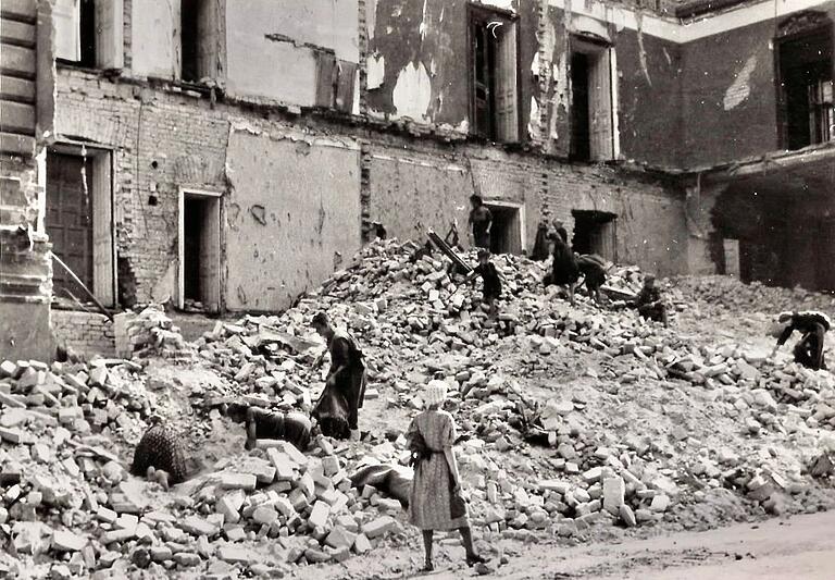 Menschen suchen in den Trümmern eines Hauses nach ihren Habseligkeiten, festgehalten von Joseph Dieves.