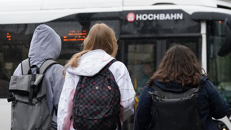 Busverkehr       -  Zwei Schülerinnen und ein Schüler warten in Hamburg auf einen Bus. (Symbolbild)