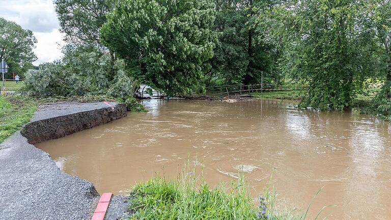 Am Sonntag nach dem Hochwasser in Schwarzach am 9. Juli 2021 sieht man die abgesunkene Brücke über die Schwarzach und die weggespülten Uferteile.