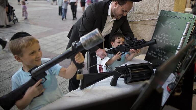 Kindheit in Nahost: Kinder schauen sich Waffen der israelischen Polizei an. Foto: Abir Sultan       -  Kindheit in Nahost: Kinder schauen sich Waffen der israelischen Polizei an.