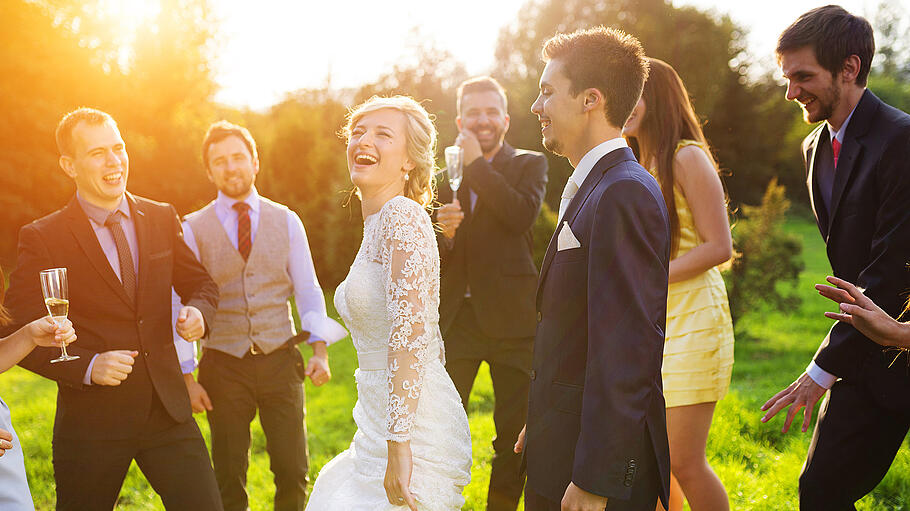 Newlyweds with guest on their garden party       -  Full length portrait of newlywed couple dancing and having fun with bridesmaids and groomsmen in green sunny park