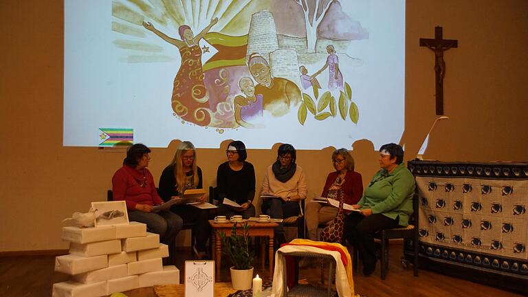 In szenischen Gesprächen vermittelte die Liturgie zum Weltgebetstag Einblicke in das Leben von Frauen in Simbabwe. Über der Gesprächsrunde das Symbolbild des diesjährigen Weltgebetstags.