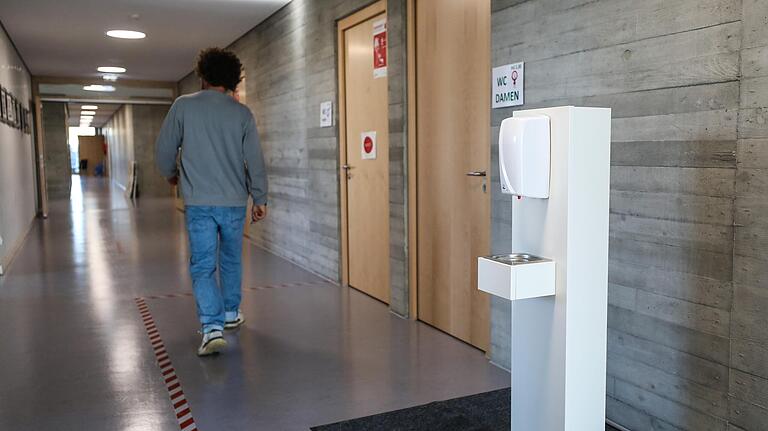 Ein Lehrer geht in einer Schule an einem Desinfektionsmittel-Spender vorbei, der dort zum Schutz gegen das Corona-Virus platziert wurde. Ein Lehrer geht in einer Schule an einem Desinfektionsmittel-Spender vorbei, der dort zum Schutz gegen das Corona-Virus platziert wurde. 