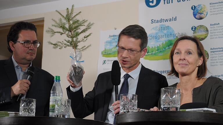 So schaut ein Setzling aus, wenn er sechs Jahre alt ist: Oberbürgermeister Sebastian Remelé (Mitte), Befürworter der Landesgartenschau-2026-Pläne,&nbsp; hatte zur Podiumsdiskussion 'Stadtwald oder Millionengrab Landesgartenschau' eine junge Fichte mitgebracht, um zu illustrieren, wie lange ein Baum braucht, bis er ausgewachsen ist. Links Moderator Frank Farenzki, rechts Ulrike Schneider, die beim Bürgerbegehren für einen Stadtwald statt LGS kämpft.