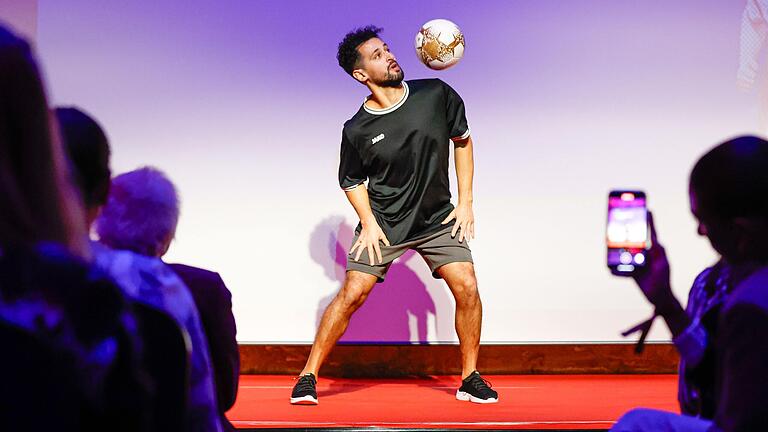 Fußball-Freestyler Mo Jamal zeigte eine Akrobatik-Show mit dem Ball und stellte in Würzburg einen neuen Rekord auf, einen hoch geworfenen Ball im Handstand mit den Beinen zu fangen. Fußball-Freestyler Mo Jamal zeigte eine Akrobatik-Show mit dem Ball und stellte in Würzburg einen neuen Rekord auf, einen hoch geworfenen Ball im Handstand mit den Beinen zu fangen.