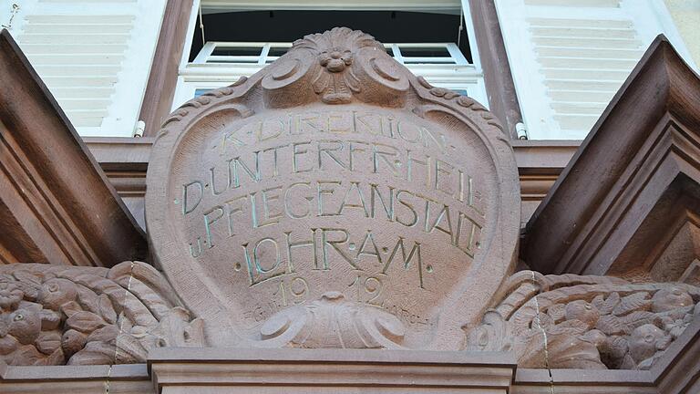 Die Inschrift über dem Portal des Verwaltungsgebäudes weist auf die Inbetriebnahme der neu erbauten Heil- und Pflegeanstalt in Lohr im Jahr 1912 hin. Die Inschrift über dem Portal des Verwaltungsgebäudes weist auf die Inbetriebnahme der neu erbauten Heil- und Pflegeanstalt in Lohr im Jahr 1912 hin.
