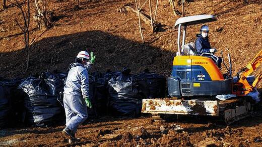 Weg mit der Erde: In Schutzanzügen und mit Baggern tragen Arbeiter in der Stadt Iitate verseuchte Erde ab und packen sie in Säcke.