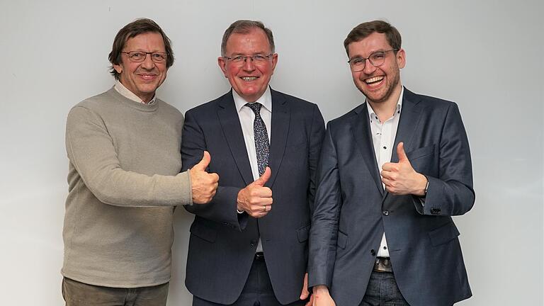 Bezirkstagspräsident Erwin Dotzel, der scheidende Popularmusik-Beauftragte Peter Näder (links) und sein Nachfolger Benjamin Haupt (rechts) zeigen „Daumen hoch“ für die Popularmusikförderung des Bezirks Unterfranken.