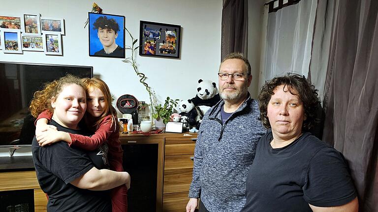 Yvonne und Thomas Ressel, sowie ihre Töchter Zoé und Mirjam (von links) vor dem Bild von Jan-Luca und einem Schrank, auf dem viele Sachen stehen, die ihr Sohn gerne hatte