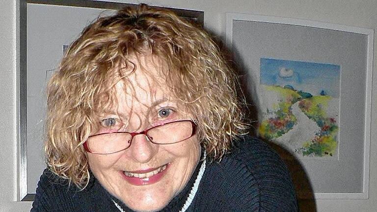 Anneliese Eva Friedrich deutet auf ihr im Flyer der Stadt Marktheidenfeld zum Kunstpreis 2016 abgebildetes Werk.