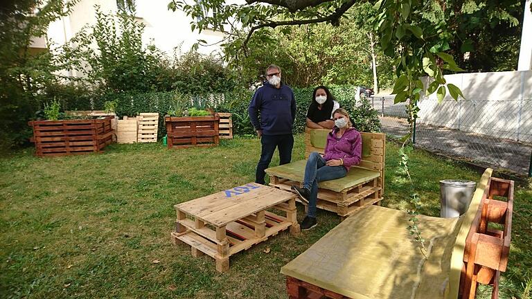 Kurt Pregitzer (links) mit einer Projektteilnehmerin und Ernährungsberaterin Verena Klopf (rechts) genießen die selbst gebaute Sitzgruppe.