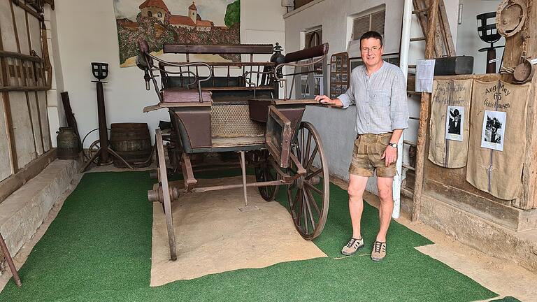 Albin May neben seinem Kutschenwagen, umringt von Sammelstücken aus dem 19. und 20. Jahrhundert.