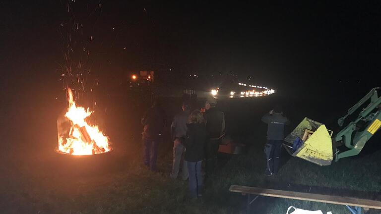 Das Mahnfeuer der Landwirte an der B27 in Richtung Hainbuche/Sodenberg, organisiert von den Ortsverbänden Weyersfeld und Weickersgrüben. Teilgenommen haben ca. 70 Personen. Im Hintergrund sieht man den Korso mit 25 Schleppern aus der Region, der vom Sammelpunkt in Weyersfeld zum Feuerplatz fährt.