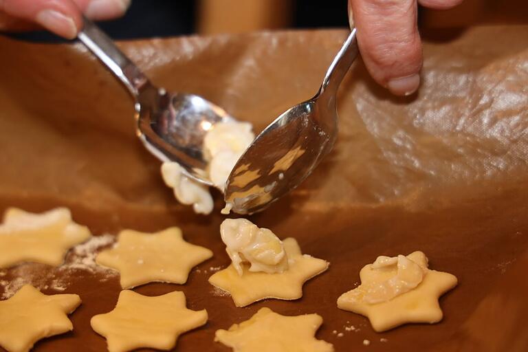 Es braucht Geduld und Präzision, um die Mandel-Eischnee-Masse auf die ausgestochenen Plätzchen zu setzen.