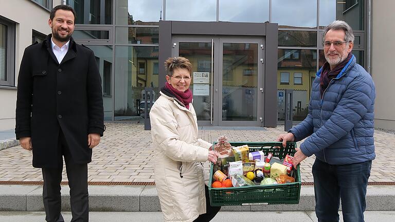 Wernecks Bürgermeister Sebastian Hauck (links) präsentiert zusammen mit Ernst Gehling von der Tafel Schweinfurt und Rathaus-Mitarbeiterin Brigitte Rösch-Ibel eine Kiste mit Lebensmitteln, die Tafel-Kunden für einen geringen Beitrag erhalten.