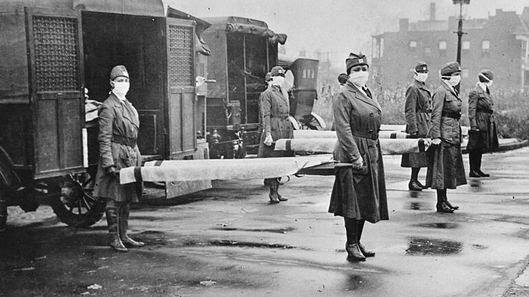 Mitarbeiterinnen des St. Louis Red Cross Motor Corps in St. Louis (USA), die sich mit Masken und Bahren im Oktober 1918 auf die Versorgung der Opfer der Grippeepidemie vorbereiten.&nbsp;