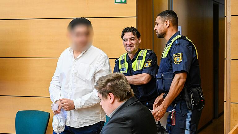 Ein 24-jähriger Mann wird mit Handfesseln in den Gerichtssaal gebracht. Er muss sich wegen versuchter Tötung eines Polizisten und gefährlicher Körperverletzung vor dem Landgericht Würzburg verantworten. Ein 24-jähriger Mann wird mit Handfesseln in den Gerichtssaal gebracht. Er muss sich wegen versuchter Tötung eines Polizisten und gefährlicher Körperverletzung vor dem Landgericht Würzburg verantworten.