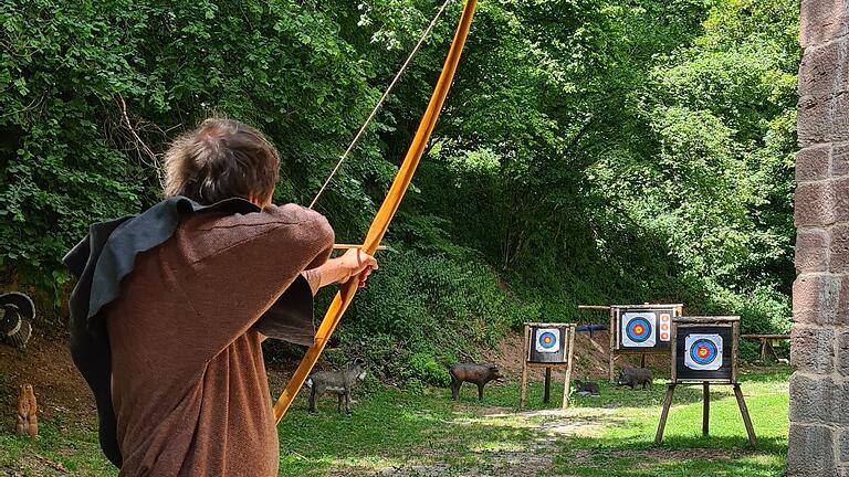 Wie Robin Hood: Ein Schütze im mittelalterlichen Gewand übt Bogenschießen im Burggraben der Henneburg in Stadtprozelten.