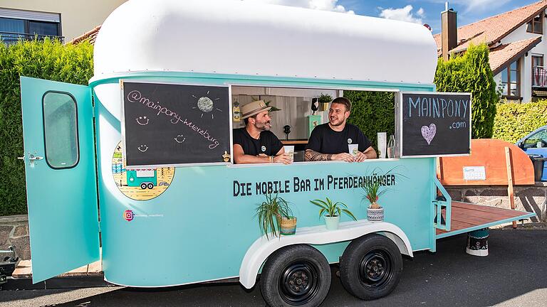 Florian Baumeister (l.) und Louis Königer aus Kürnach sitzen in der selbstgebauten Bar im Pferdeanhänger.