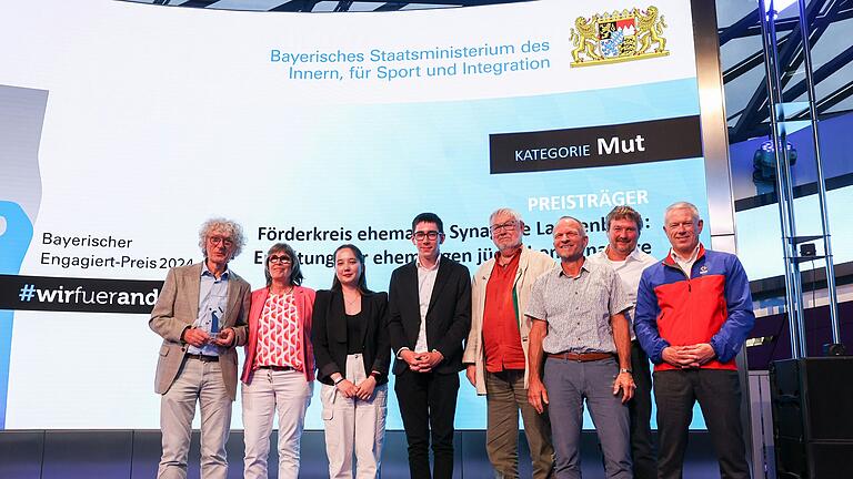 Bayerns Innenminister Joachim Herrmann verleiht den bayerischen 'Engagiert-Preis 2024' für herausragende Leistungen im Ehrenamt für die Sicherheit der Menschen in Bayern in der BMW-Welt in München (von links): Georg Schirmer, Daniela Schirmer, Maxime Hirt, Marcel Schwarz, Günther Rösch, Christof Rösel, Peter Kretzinger und der Laudator Thomas Lobensteiner.