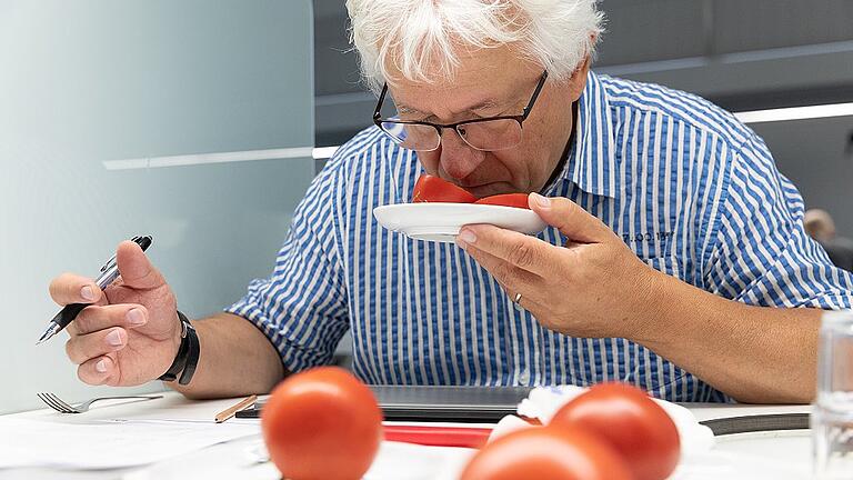 Noch nicht essen, nur riechen!&ldquo;, Martin Schulz bremst den Appetit. Leuchtend rot und prall liegen die Tomaten auf Tellerchen bereit. Aber bei der Mission Geschmack an diesem Vormittag im Veitshöchheimer Sensorikzentrum geht?s um genaues Beschreiben, nicht ums Essen. Zwölf Prüfer der Landesanstalt für Weinbau und Gartenbau (LWG) sind  zusammengekommen, um bayerische Tomaten zu verkosten. Genauer gesagt: um sie sensorisch zu bewerten. Fruchtig, krautig oder grün? Süßlich, würzig oder stechend? Mit dem Geruch der ganzen Frucht geht die Prüfung los. &bdquo;Gibt es schon Meinungsbilder?&ldquo;, fragt Martin Schulz in die Runde. Die Prüfer halten sich die Tomaten vor die Nase, schnüffeln, grübeln. &bdquo;Die riecht nur nach Geiz!&ldquo; &ndash; &bdquo;Chemisch oder muffig riecht sie gar nicht, würzig aber auch nicht wirklich.&ldquo; &ndash; &bdquo;Fruchtig? Überhaupt nicht. Eigentlich fast neutral.&ldquo; Gemurmel und Meinungsdurcheinander im Labor. Zur Einstimmung hat Prüfleiter Martin Schulz die Runde erst einmal an gelben Cocktailtomaten riechen und darüber gemeinsam diskutieren lassen. Nachher, bei den roten Tomaten, um die es heute geht, riecht, schmeckt, bewertet, beschreibt jeder für sich. &bdquo;Ich hab&lsquo; extra wenig Kaffee getrunken heute&ldquo;, sagt einer. &bdquo;Nur zwei Schluck.&ldquo; Seit knapp einem Jahr gibt es an der Landesanstalt in Veitshöchheim das Sensorikzentrum, das aussieht wie ein fensterloses Zahntechnikerlabor. Ziemlich steril und alles in Weiß, nichts soll ablenken, beeinflussen, stören. Milchglasscheiben trennen die 24 Prüfplätze samt Waschbecken, damit keiner beim Schnuppern und Gustieren gestört wird &ndash; und nicht beim Nebenmann auf den Prüfbogen spickt. Die LWG ist dabei, ein sensorisches wissenschaftliches Panel aufzubauen. Denn bei Äpfeln, Spargel, Tomaten und anderem Gemüse ist vieles eine Frage des Geschmacks. Aber die Aromaeindrücke einzeln zu erkennen, sie objektiv zu beschreiben, nüchtern einzuordnen &ndash; das muss man können. Also: erst einmal lernen und trainieren. Deshalb schult die LWG interessierte Mitarbeiter in Sachen Sensorik. Und deshalb sitzen Weinanalytiker und Rebschnittexperten aus Veitshöchheim an diesem Morgen mit Gärtnern und Gemüseexperten der Versuchsanlage in Bamberg zusammen und riechen an sechs Rispentomaten, am Nachmittag dann an sechs Naschtomaten. Inzwischen durften die Prüfer die Tomaten aufschneiden und am Inneren schnuppern. &bdquo;Jetzt riecht?s aber&ldquo;, sagt einer. Krautig? Fruchtig? Stechend? Chemisch? Martin Schulz will es genau wissen. &bdquo;Eine gute Sorte riecht typisch Tomate&ldquo;, sagt der Prüfpanelleiter. Dem Versuchsingenieur am Gemüsebauversuchsbetrieb in Bamberg geht es um eine Standortbestimmung der bayerischen Tomate. Vier Sorten Rispentomate aus sechs mittel- und oberfränkischen Anbaubetrieben hat er für die Prüfung mitgebracht. Sie wurden mit unterschiedlichen Strategien, mit unterschiedlichen Nachttemperaturen angebaut, zu verschiedenen Zeitpunkten geerntet. Was Schulz wissen will: Schmeckt man das?  Hinter der Probeverkostung im Sensorikzentrum stehen große Zahlen &ndash; und die Überlegung, wie sich bayerisches Obst und Gemüse (noch) besser am Markt halten lässt.  In den vergangenen Jahren hat die Anbaufläche der roten Früchte stark zugenommen, sagt der Versuchsingenieur. 2015 bauten laut Statistischem Landesamt 275 bayerische Betriebe auf gut 52 Hektar unter hohen begehbaren Schutzabdeckungen Tomaten an und ernteten 14 500 Tonnen. Zwei Jahre später waren es einschließlich Gewächshäusern 76 Hektar Anbaufläche, auf denen 278 Betriebe 23 270 Tonnen ernteten. Aber, sagt Schulz: &bdquo;Die Leute essen ja nicht mehr Tomaten.&ldquo; 19 Kilo sind es den Statistiken zufolge pro Kopf pro Jahr, davon die Hälfte als &bdquo;Frischtomate&ldquo;, der Rest in verarbeiteter Form im Ketchup und auf Pizza. Nur ein Bruchteil davon komme aus Deutschland, sagt Schulz: &bdquo;Ein Kilo&ldquo;.   Aber jetzt &bdquo;explodiere&ldquo; der Anbau in Bayern, das heißt: Die bayerische Tomate muss die importieren Früchte verdrängen. Allein China, weltgrößter Tomatenanbauer, bringt jährlich 50 Millionen Tonnen auf den globalen Markt. Schulz sagt: &bdquo;Man braucht ein regionales Produkt, das gut schmeckt.&ldquo; Deshalb heißt die Frage an diesem Vormittag: &bdquo;Wie stellt sich die bayerische Tomate dar?&ldquo; Die sechs Rispentomaten sind aufgeschnitten. &bdquo;So, jetzt geht?s ans Schmecken.&ldquo; Süß, sauer, bitter? Fruchtig, würzig, krautig, grün? &bdquo;Geschmack beginnt an der Zunge&ldquo;, sagt Prüfleiter Martin Schulz in die geschäftige Stille. Die Prüfer kauen, schmecken, spülen den Mund mit Wasser aus. Ob die Tomate einen Nachgeschmack hat? Ob das Fruchtfleisch weich, saftig oder schalenfest ist?  &bdquo;Schmecken Sie weiter!&ldquo;, sagt  Martin Schulz, &bdquo;Wie ist Ihr Eindruck im Rachenraum?&ldquo; Und das Mundgefühl? Mehlig, wässrig, brennend, adstringierend?    &bdquo;Positiv&ldquo;, sagt einer. &bdquo;Die hier war etwas wässrig&ldquo;, meint der Nebenmann. Ganz am Schluss geht?s darum, wie den Prüfern die jeweilige Tomate gefällt. &bdquo;Jetzt dürfen Sie subjektiv sein&ldquo;, sagt Schulz und bittet um Akzeptanzwerte von 1 = schlecht bis 9 = sehr gut.  Vor zehn Jahren haben die Gemüseanbauer der Landesanstalt schon einmal Tomaten professionell verkosten lassen, vom Julius-Kühn-Institut in Quedlinburg. Das am Bundesforschungsinstitut für Kulturpflanzen entwickelte Prüfformular nutzt die LWG jetzt wieder.  &bdquo;Wir wissen, was gut ist und was nicht&ldquo;, sagen die Bamberger Gemüsegärtner Josef Eichhorn und Wolfgang Hollmach und beugen sich nach knapp einer Stunde über die Reste der geprüften Tomaten. Euphorie sieht anders aus. &bdquo;Überraschend, dass die alle nach nichts riechen.&ldquo; Kollege Hermann Foos stimmt  zu. &bdquo;Das war alles nichts.&ldquo; Es brauche einige Übung, seinen Geschmack zu schulen, sagt LWG-Präsident Dr. Hermann Kolesch über das wissenschaftliche Panel, das die Landesanstalt intern gerade aufbaut. Allein die Grundgeschmacksarten salzig, sauer, bitter und süß voneinander zu unterscheiden &ndash; was gemeinhin nicht schwierig scheint, treibt den Teilnehmern im Sensorikzentrum Schweißperlen auf die Stirn. Schnell wackeln die Geschmackseindrücke, schnell wird man unsicher bei der Charakterisierung, die objektiv sein soll. &bdquo;Es ist nicht immer schön, was rauskommt&ldquo;, sagt Schulz über die ersten Ergebnisse angehender Prüfer beim Sinnestraining.  Wein, Brände, Käse, Äpfel, Spargel, Honig und nun eben Tomaten sind im ersten Jahr im Sensorikzentrum schon geprüft worden. Im Hintergrund immer mit der Frage, wie das regionale Obst und Gemüse besser am Markt ankommen kann. Welche Sorten bringen im Frühjahr, Sommer oder Herbst das beste Tomaten- oder Apfelaroma zum Verbraucher? Welcher Spargelboden verspricht den besten Genuss? &bdquo;Die Ergebnisse liefern Ansätze, wie die Produktqualität verbessert werden kann, also Sortenwahl, Anbaustrategie, Einsatz von geschmacksfördernden Mittel&ldquo;, sagt Martin Schulz. &bdquo;Wir wollen Gründe finden, warum ein Produkt ankommt oder schlecht ist.&ldquo;  Er selbst weiß an diesem Vormittag übrigens auch nicht, von welchen Betrieben die Rispentomaten stammen und wie sie angebaut wurden. &bdquo;Das würde mich nur beeinflussen.&ldquo; Am Nachmittag noch die Cocktailtomaten &ndash; dann sind die Geschmacksnerven endgültig erlahmt. In Bamberg werden die LWG-Mitarbeiter die Ergebnisse auswerten &ndash; und an die Gärtnereien weitergeben und selbst Schlüsse daraus ziehen für Anbau und Zucht. Im September gibt?s wieder im Sensorikzentrum die nächste Runde &ndash; für Prüfer und Tomaten.