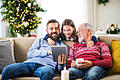 Small girl and her father and grandfather sitting on a sofa at Christmas, using tablet.       -  Alles, was in der Region passiert, aktuell und schnell auf dem Tablet lesen!