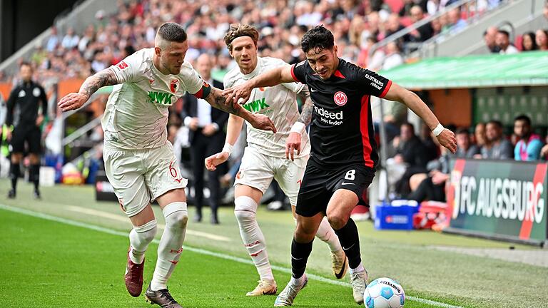 FC Augsburg - Eintracht Frankfurt       -  Viel Kampf in Augsburg: Frankfurts Farès Chaïbi (r) gegen FCA-Kapitän Jeffrey Gouweleeuw (l) und Kristijan Jakic.