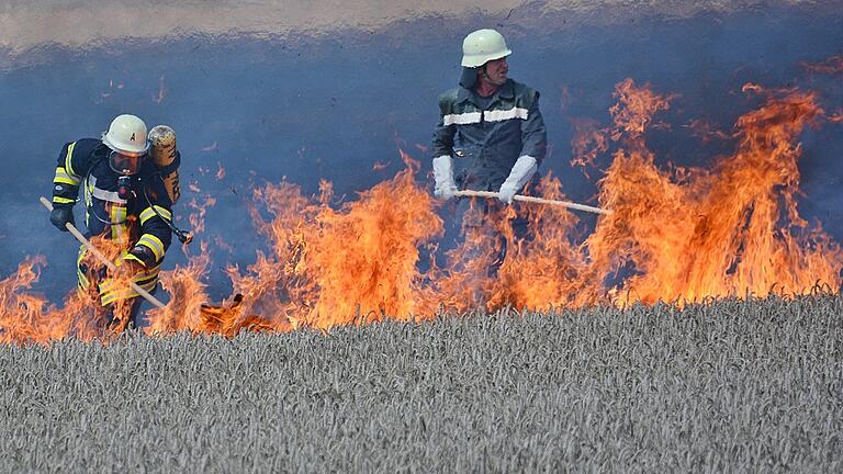 Auf trockenen Feldern hat Feuer ein leichtes Spiel: Feuerwehrleute versuchen den Brand mit sogenannten Waldbrandpatschen in Schach zu halten, bis die Versorgung mit Löschwasser steht.