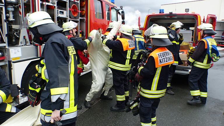Mit vereinten Kräften helfen die Kameraden vor Ort den Atemschutzträgern beim Überziehen der Schutzanzüge. Mit vereinten Kräften helfen die Kameraden vor Ort den Atemschutzträgern beim Überziehen der Schutzanzüge.